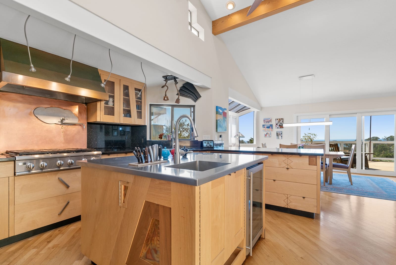 Custom wood kitchen with island, copper backsplash, and views toward the dining room
